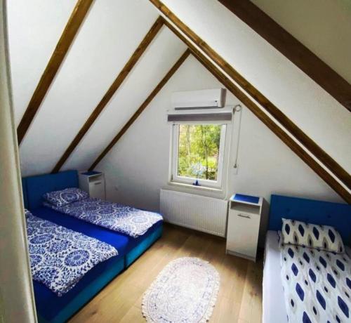a attic room with two beds and a window at Vila Dolina Izvora in Sarajevo