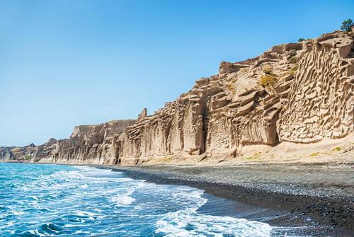 a rocky beach with the ocean next to it at Almond Deluxe Suite in Santorini