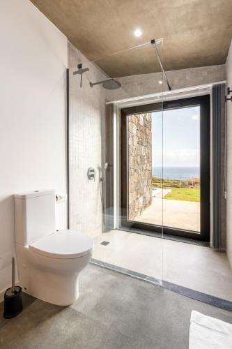 a bathroom with a toilet and a large window at Casa Al Mare in Canto da Areia