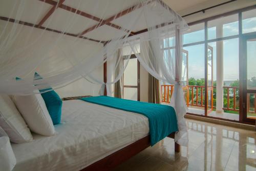 a bedroom with a canopy bed and a balcony at Savenrose Beach Villa in Matara