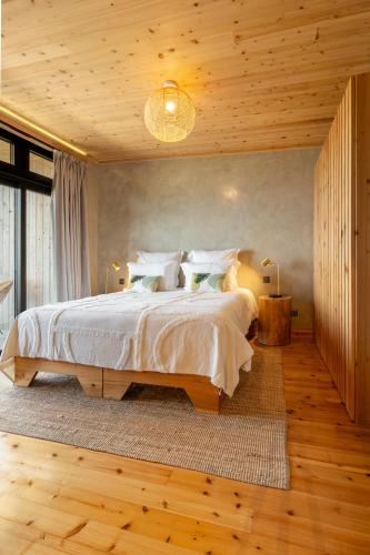 a bedroom with a large bed and wooden floors at Casa da Faia in São Roque do Pico