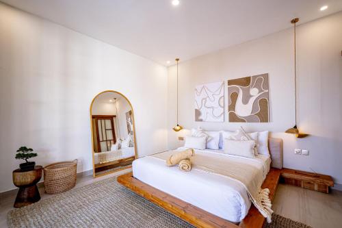 a bedroom with a large white bed and a mirror at Villa Ume Seseh in Munggu