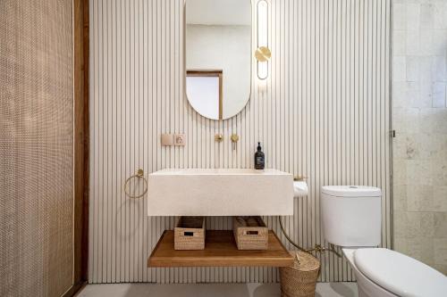 a bathroom with a sink and a mirror and a toilet at Villa Ume Seseh in Munggu