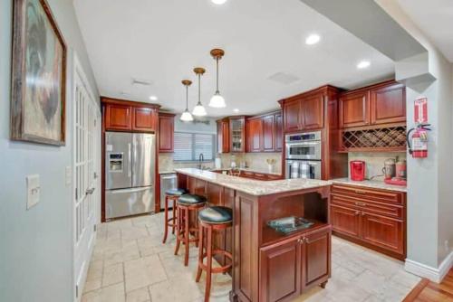 a large kitchen with wooden cabinets and bar stools at Home with pool by Dream Vacation in Fort Lauderdale
