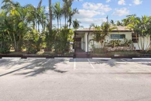 a house with a gate and a building with trees at Beach Apart by Dream Vacation unit 1 in West Palm Beach