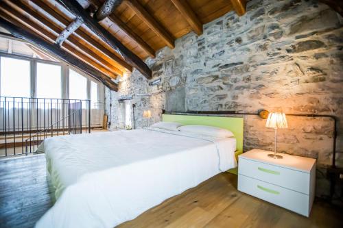 a bedroom with a large bed and a stone wall at Borgo Molina in Faggeto Lario 