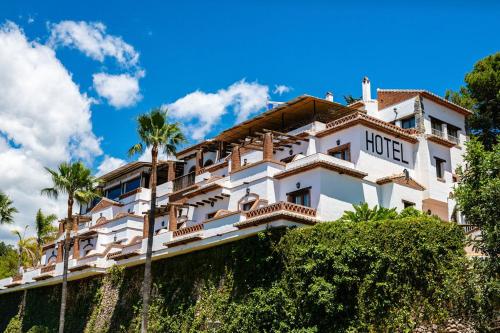 a hotel on top of a hill with palm trees at Hotel Rural Almazara in Frigiliana