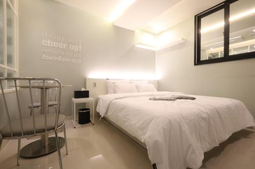 a white bedroom with a bed and a mirror at 호텔 꿀밤스테이 in Sacheon