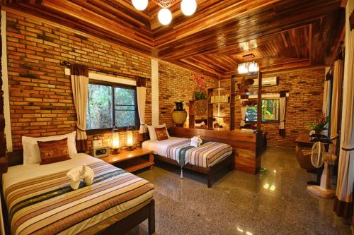 a bedroom with two beds and a brick wall at Hotel Khaosok and Spa in Khao Sok