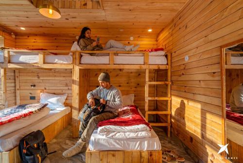 a man and a woman sitting in a room with bunk beds at Zostel Homes Gadagushaini, Jibhi in Jibhi