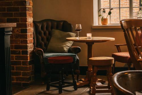a chair and a table in a bar with a glass of wine at Boot & Shoe in Flintham