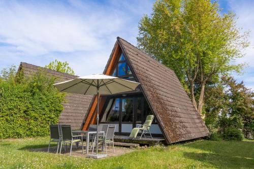 a cabin with a roof with chairs and an umbrella at Bodenseehäusle in Immenstaad am Bodensee