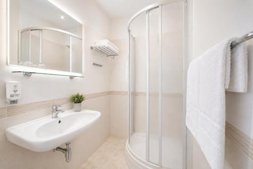 a white bathroom with a sink and a shower at Hotel Uno Prague in Prague