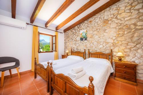 a bedroom with a bed and a stone wall at Villa Cal Apostol in Pollença