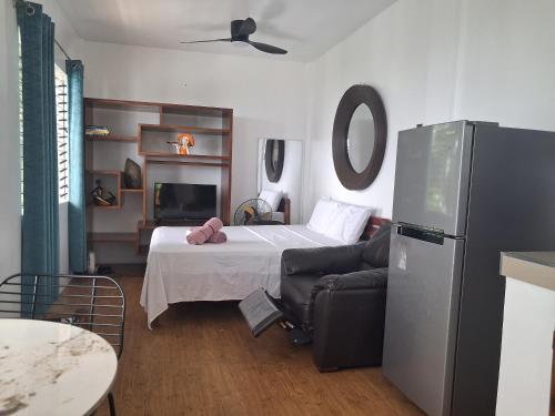 a bedroom with a bed and a couch and a refrigerator at el balcon camiguin in Mambajao