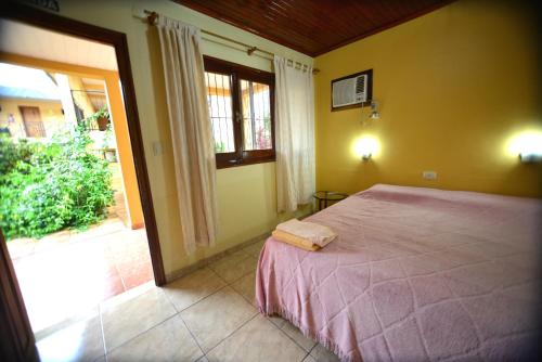 um quarto com uma cama e uma grande janela em Hotel Lilian em Puerto Iguazú