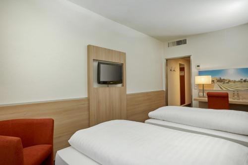 a hotel room with two beds and a tv at H+ Hotel Darmstadt in Darmstadt