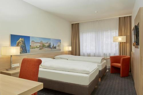 a hotel room with two beds and a desk at H+ Hotel Darmstadt in Darmstadt