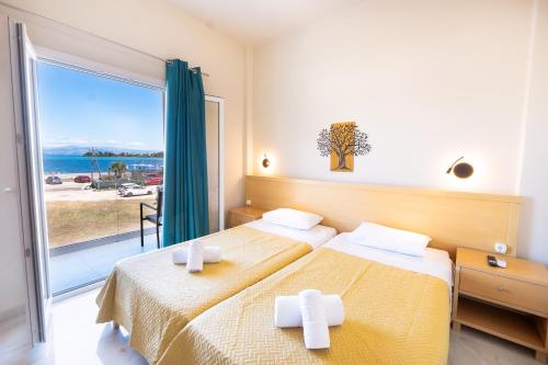 a hotel room with two beds and a large window at Penelope - Sea Front Studio in Gouvia