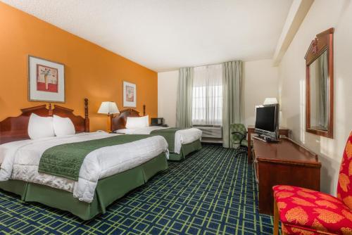 a hotel room with two beds and a television at Baymont by Wyndham Greensburg in Greensburg
