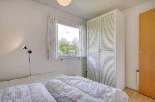 a white bedroom with a bed and a window at Beautiful bright summer cottage in Skovbyballe
