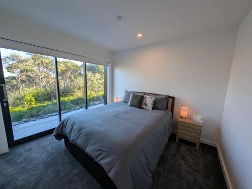 a bedroom with a bed and a large window at Gumlands Retreat in Auckland