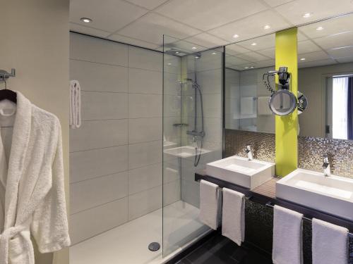 a bathroom with two sinks and a glass shower at Mercure Hotel Groningen Martiniplaza in Groningen