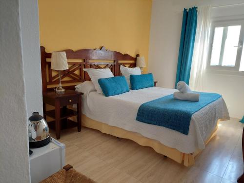 a bedroom with a large bed with blue pillows at Hotel Boutique Las Arenas in Es Cana