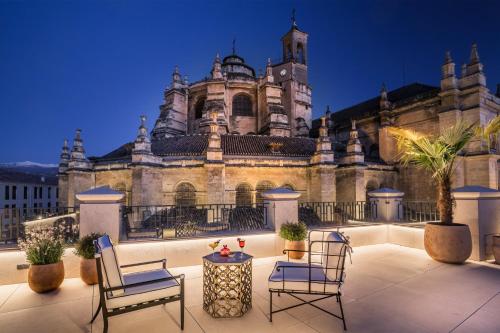 an old building with chairs and a table in front of it at Gran Hotel Claridge Granada - Preferred Hotels & Resorts in Granada
