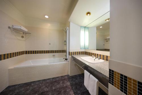 a bathroom with a tub and a sink and a mirror at Rendezvous Heritage Hotel Auckland in Auckland