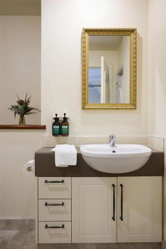 a bathroom with a sink and a mirror at Adina Heritage Christchurch in Christchurch