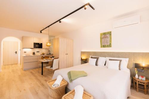 a bedroom with a large white bed and a kitchen at Apartments GoldRain in Coldrano