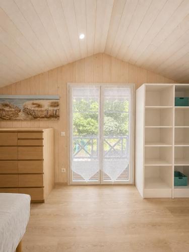 a bedroom with a large window and a bed and a door at Chalet Familial 6 personnes in Gujan-Mestras