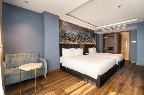 a hotel room with a large bed and a chair at The Solith Hotel Managed By Nicecy in Ho Chi Minh City