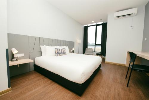 a bedroom with a large white bed and a desk at Signature by The Concept in Kuah