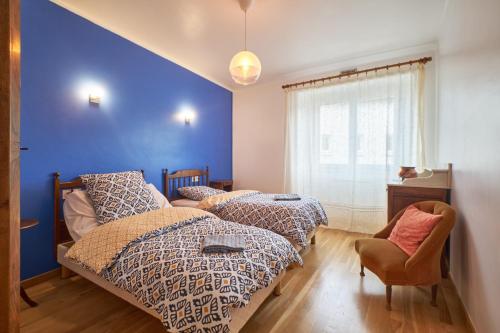 a bedroom with two beds and a blue wall at Chez Emile in Brézins