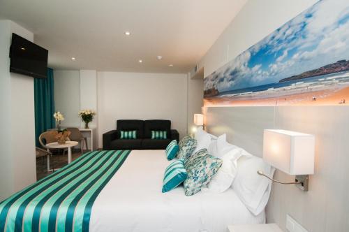 um quarto de hotel com uma cama com um cobertor verde e branco listrado em Hotel Censal em Villajoyosa