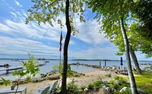 a beach with chairs and a flag on it at BEACHSIDE ON SEBAGO LIMIT 6 villa in Standish