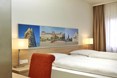 a hotel room with two beds and a painting on the wall at H+ Hotel Darmstadt in Darmstadt