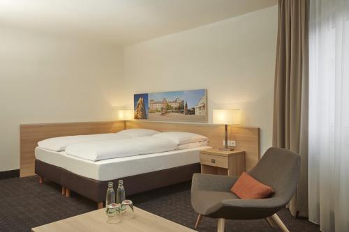 a hotel room with a bed and a chair at H+ Hotel Darmstadt in Darmstadt