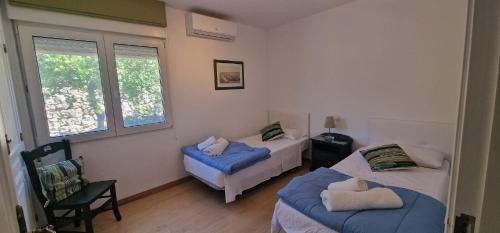a bedroom with two beds and a chair and a window at Beachfront Villa in Moraira