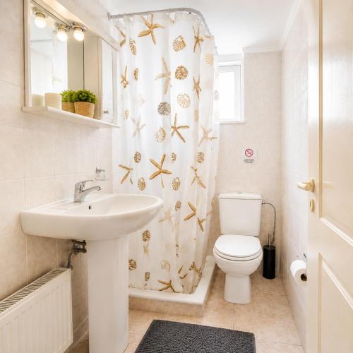 a bathroom with a sink and a toilet and a shower curtain at Sunset Apartments in Missolonghi