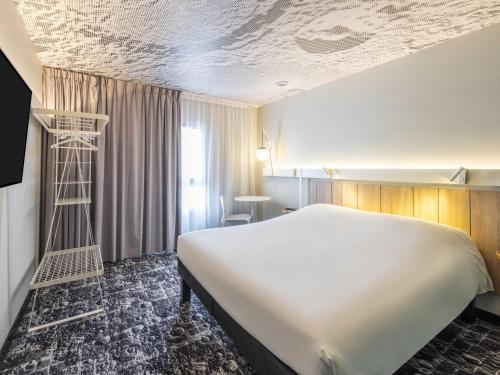 a hotel room with a large bed and a ladder at ibis Beaune Centre in Beaune