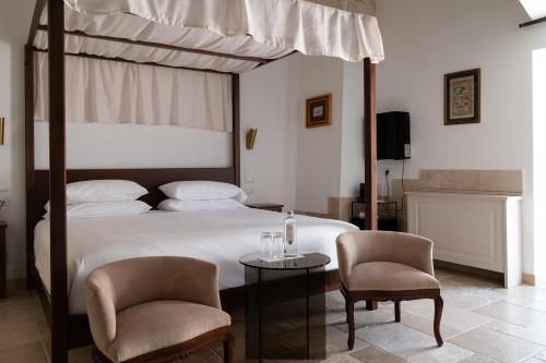 a bedroom with a bed with two chairs and a table at Dimora Mennuti in Monteparano