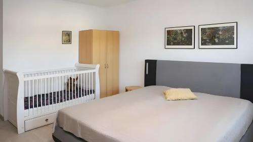 a bedroom with a white bed and a crib at Haus Eichenkrone in Bodstedt