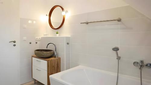 a bathroom with a tub and a sink and a mirror at Haus Eichenkrone in Bodstedt