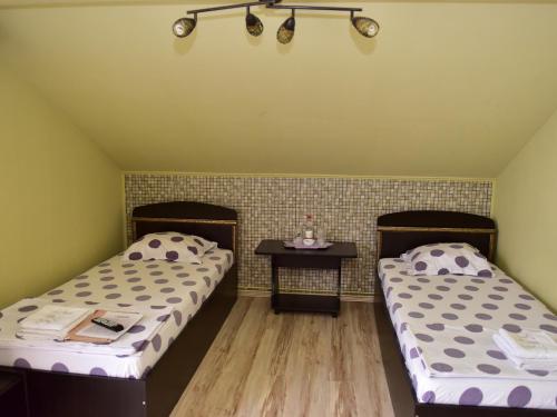 two beds in a room with a small table at Pensiunea Dely_Cios in Vălenii de Munte