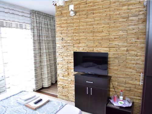 a living room with a brick wall with a tv at Pensiunea Dely_Cios in Vălenii de Munte