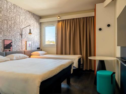 a hotel room with two beds and a window at ibis Bayonne Centre in Bayonne
