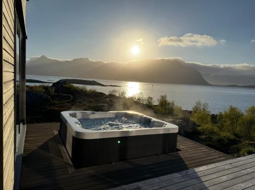 a hot tub on a deck with a view of the water at Lyngvær Arctic Pearl Lodge - Jacuzzi & Sauna - No 17 in Kleppstad